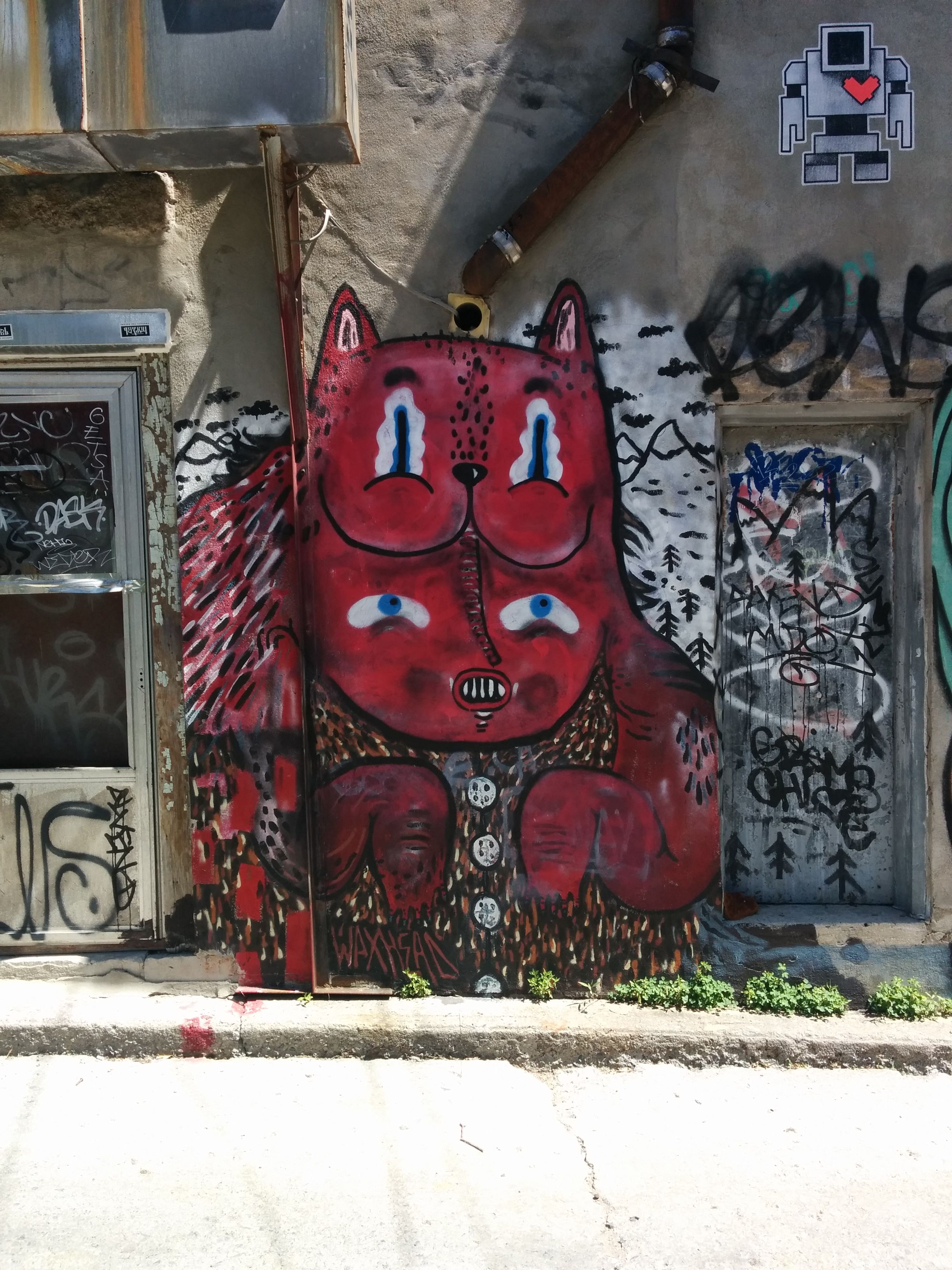 Graffiti of a 4 eyed cat like animal between two house doors